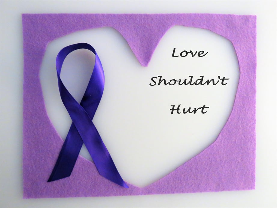 Purple ribbon on hearts; "Love Shouldn't Hurt"; abuse, domestic violence